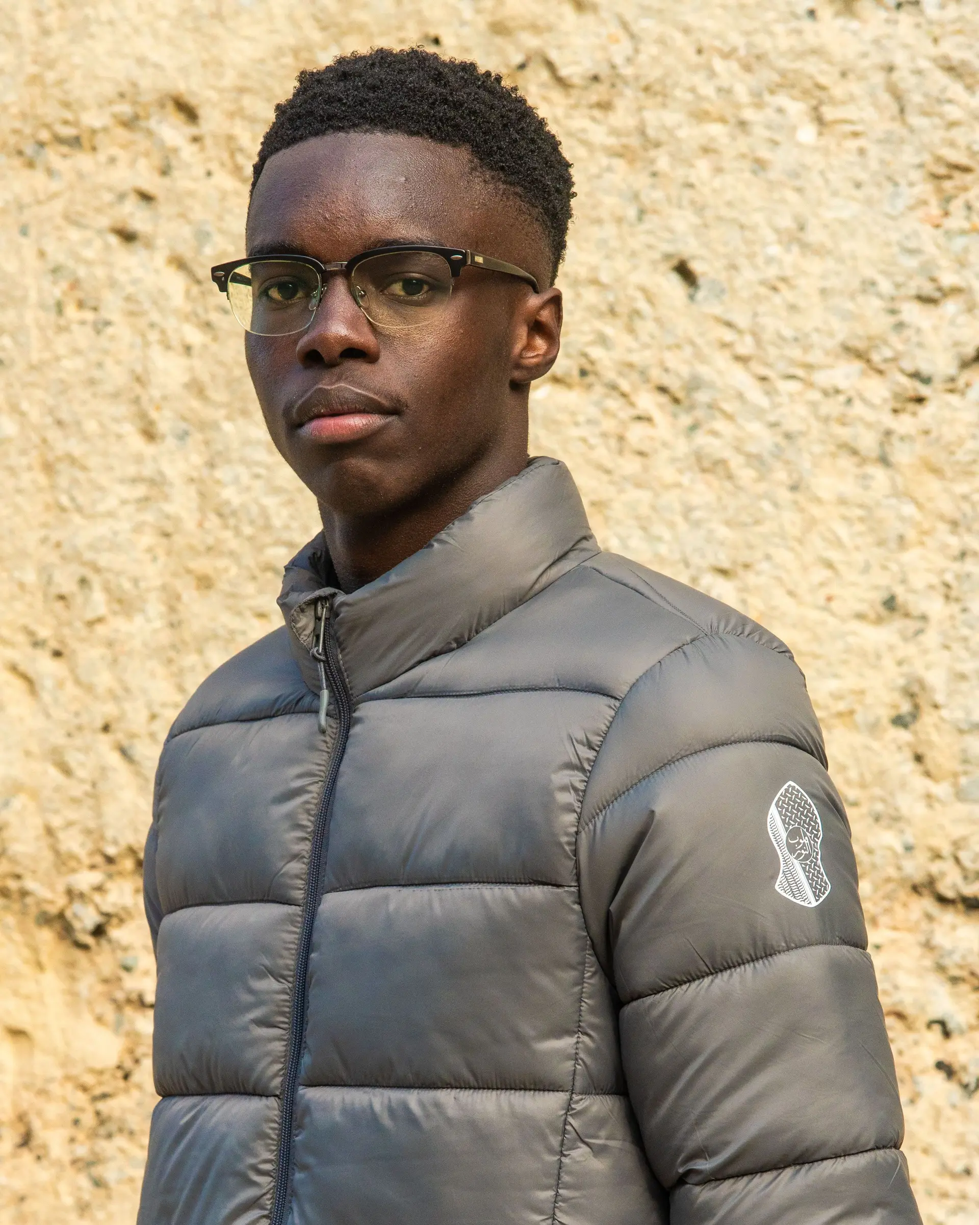 Warm grey puffer jacket, front, with the logo on the sleeve